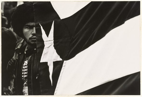 Black and white image of a young man with Puerto Rican flag